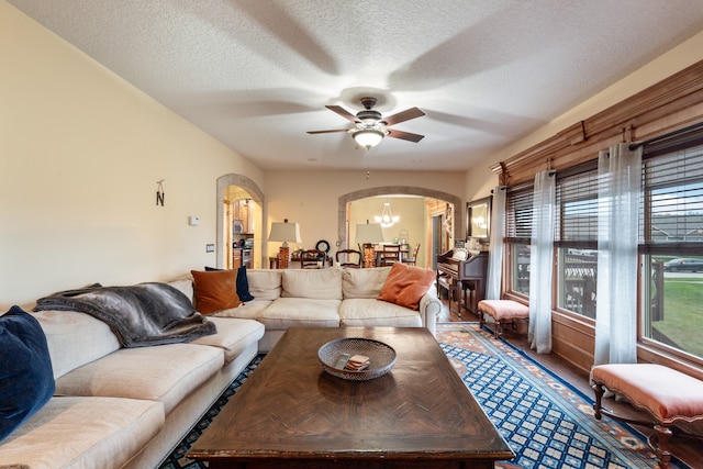 living room featuring a textured ceiling, hardwood / wood-style floors, and ceiling fan with notable chandelier