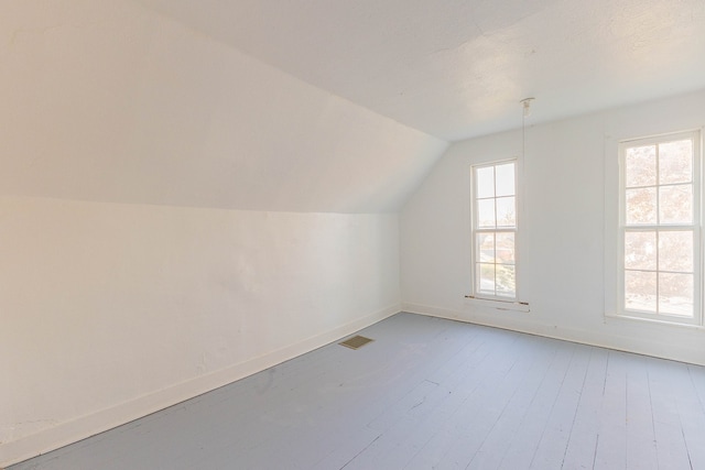 additional living space with wood-type flooring and vaulted ceiling