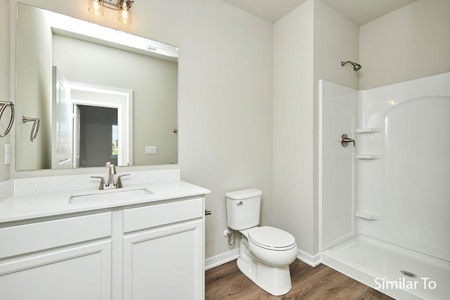 bathroom featuring hardwood / wood-style flooring, a shower, vanity, and toilet