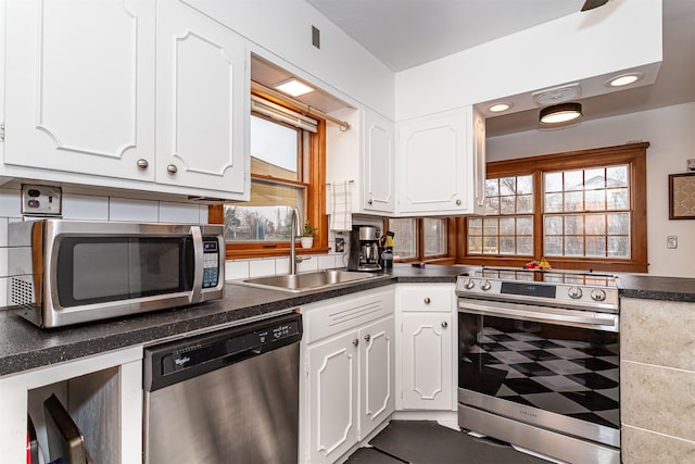 kitchen featuring white cabinets, decorative backsplash, stainless steel appliances, and sink