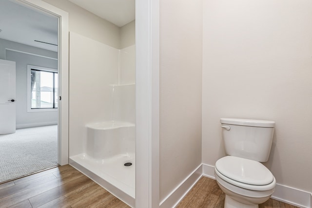 bathroom with a shower, wood-type flooring, and toilet