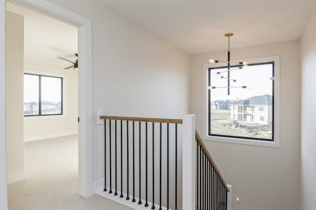 stairs with carpet flooring and ceiling fan with notable chandelier