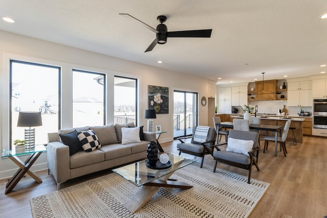 living area featuring recessed lighting, light wood-style flooring, baseboards, and a textured ceiling