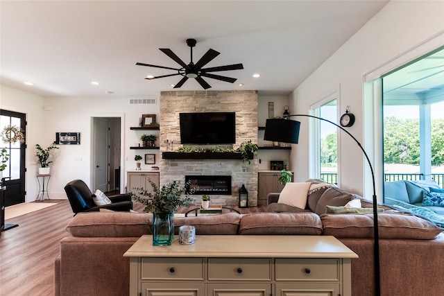 living room featuring a fireplace, light hardwood / wood-style flooring, and ceiling fan