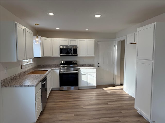 kitchen featuring hardwood / wood-style flooring, white cabinetry, and stainless steel appliances