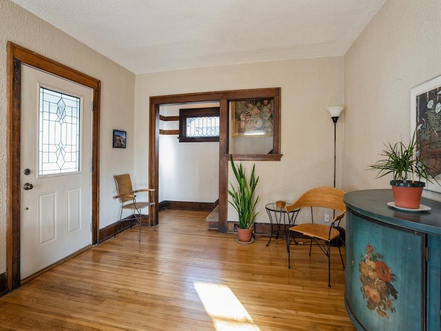 foyer featuring a textured ceiling, light wood-type flooring, and a wealth of natural light