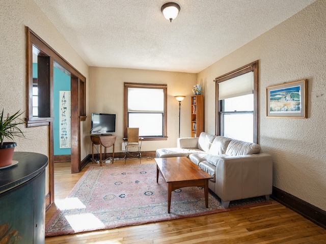 living room with a wealth of natural light, a textured ceiling, and hardwood / wood-style flooring