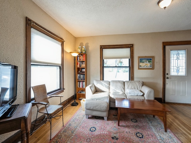 living room with a healthy amount of sunlight, wood-type flooring, and a textured ceiling