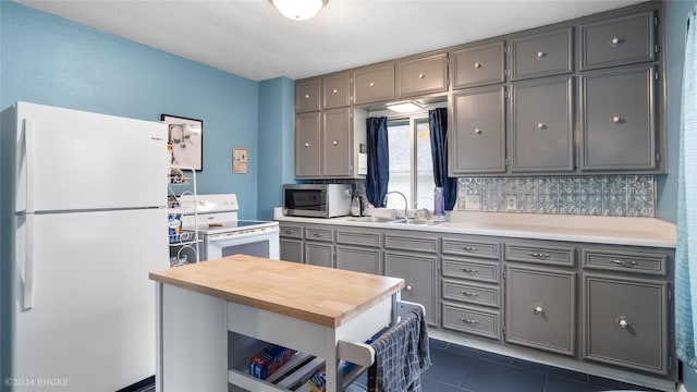 kitchen featuring dark tile patterned floors, sink, tasteful backsplash, gray cabinets, and white appliances