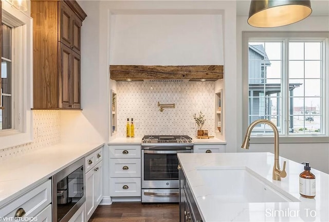 kitchen featuring sink, stainless steel gas stove, black microwave, white cabinets, and decorative backsplash