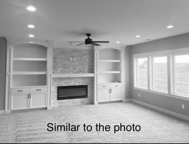 unfurnished living room with a fireplace, light carpet, built in features, and ceiling fan