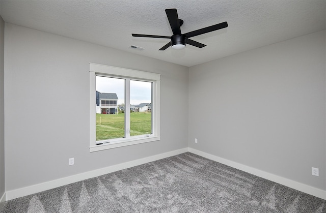 carpeted spare room featuring a textured ceiling, visible vents, baseboards, and ceiling fan