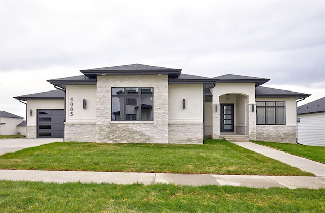 prairie-style home with a garage, stone siding, a front lawn, and stucco siding