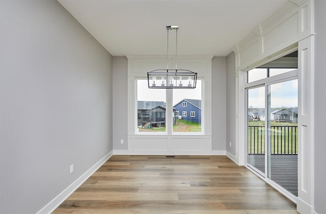 unfurnished dining area with light wood finished floors and an inviting chandelier
