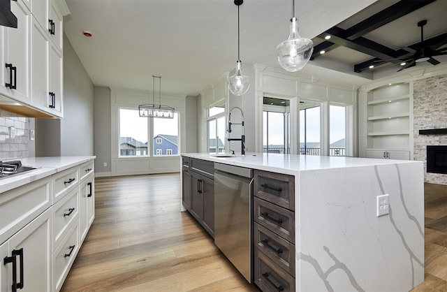 kitchen featuring a kitchen island with sink, open floor plan, built in features, white cabinetry, and dishwasher