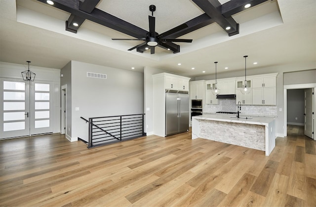 kitchen with white cabinets, visible vents, coffered ceiling, built in appliances, and decorative backsplash
