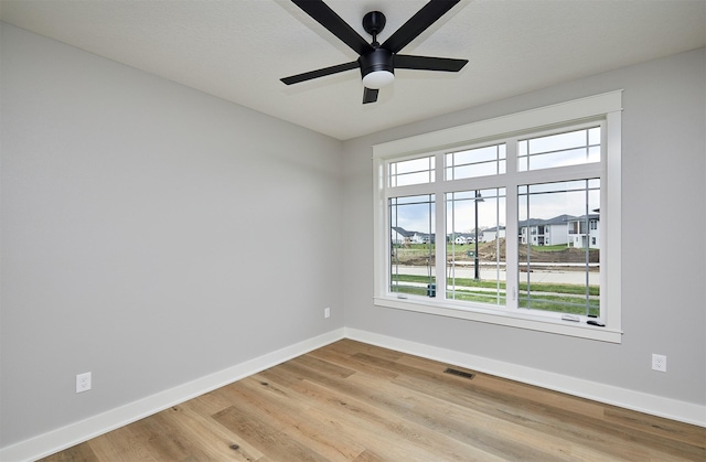 unfurnished room with ceiling fan, baseboards, light wood finished floors, and visible vents