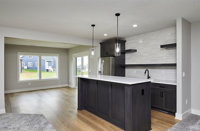 kitchen with light wood finished floors, stainless steel fridge, tasteful backsplash, open shelves, and light countertops