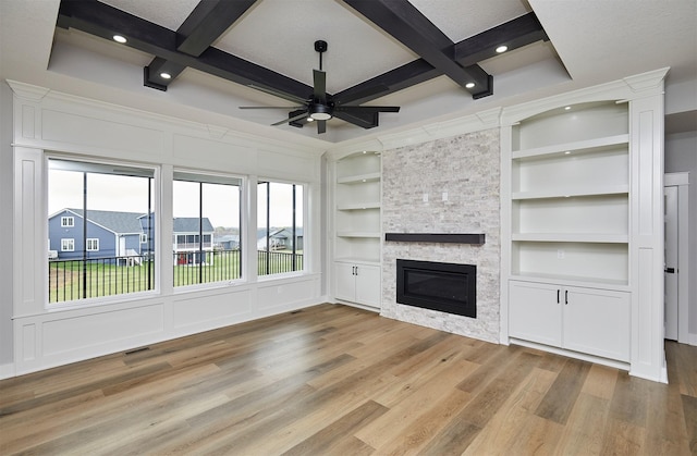 unfurnished living room with ceiling fan, coffered ceiling, wood finished floors, and a fireplace