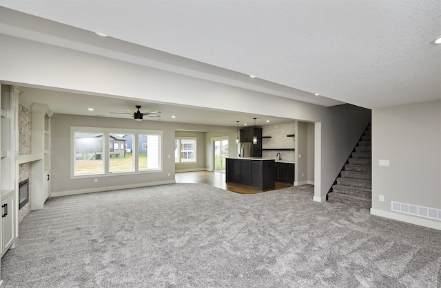 unfurnished living room with recessed lighting, carpet, visible vents, and stairway