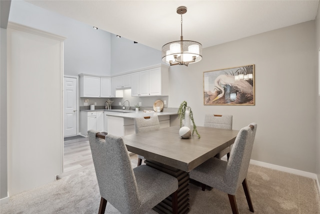 dining room featuring a notable chandelier, light wood-type flooring, sink, and high vaulted ceiling