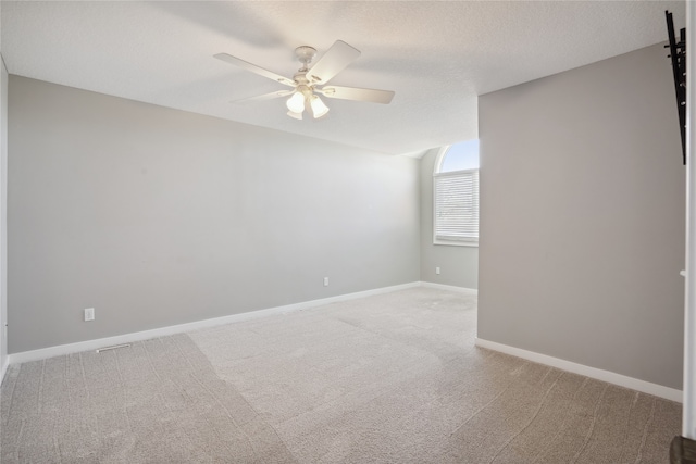 carpeted empty room featuring ceiling fan, a barn door, and a textured ceiling