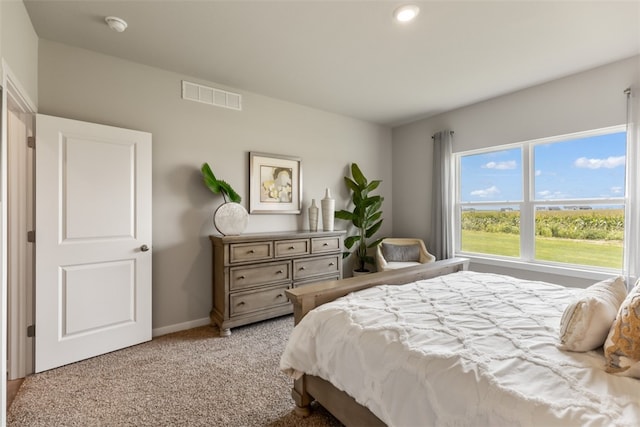 bedroom featuring baseboards, visible vents, and light colored carpet