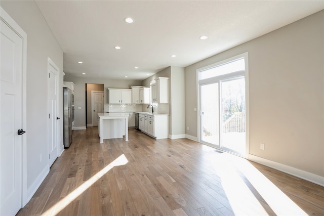 kitchen with light hardwood / wood-style flooring, white cabinetry, a kitchen island, and sink