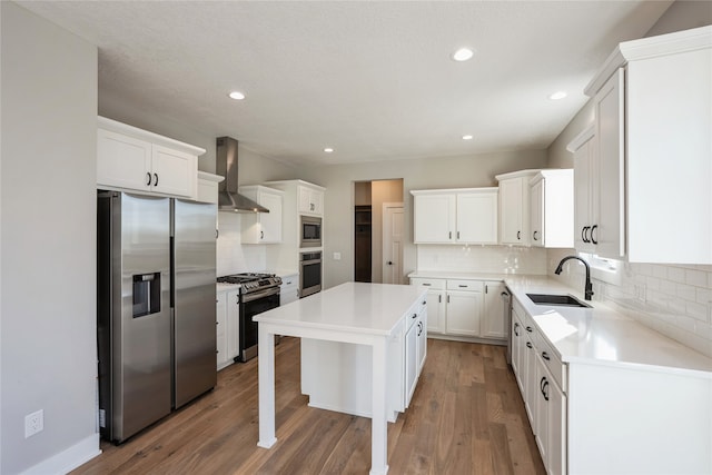 kitchen featuring a center island, stainless steel appliances, white cabinetry, and wall chimney range hood