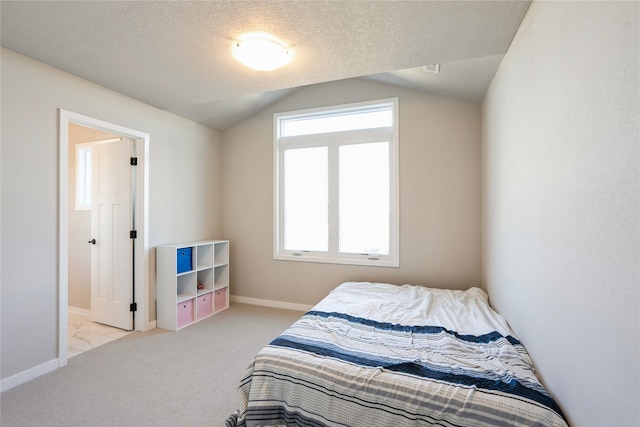 carpeted bedroom with a textured ceiling, vaulted ceiling, and multiple windows