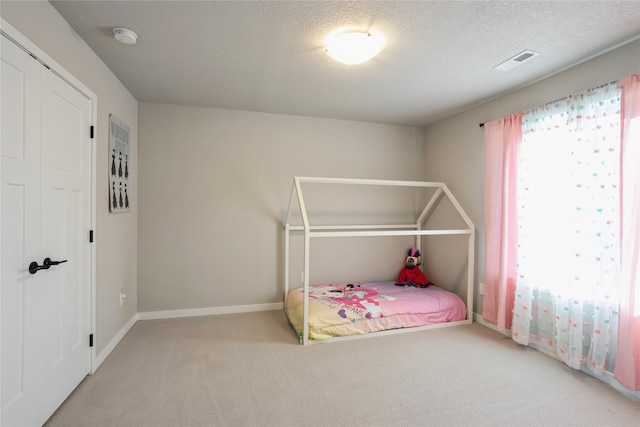 bedroom featuring light carpet, a closet, and a textured ceiling