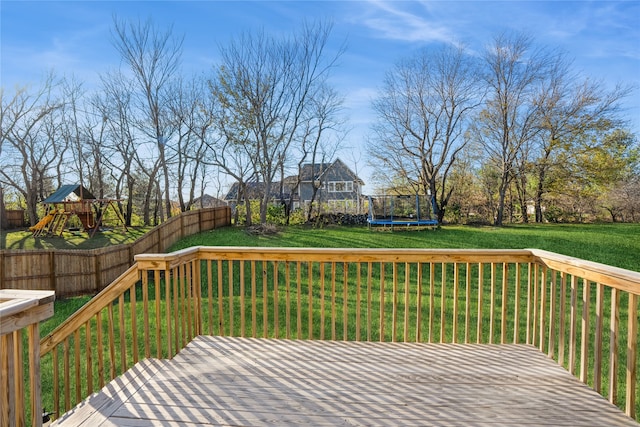 wooden terrace featuring a playground, a trampoline, and a yard