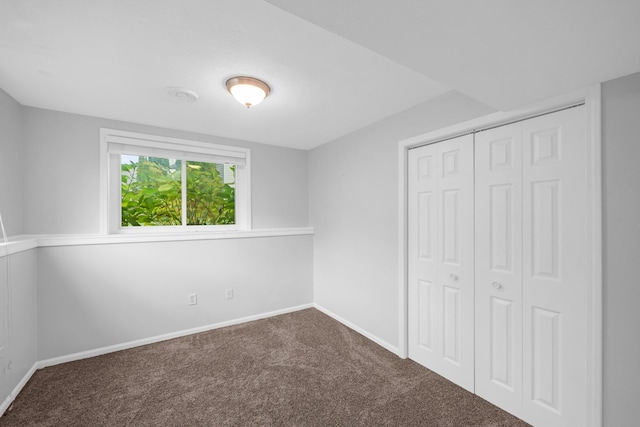 unfurnished bedroom with dark carpet and a closet