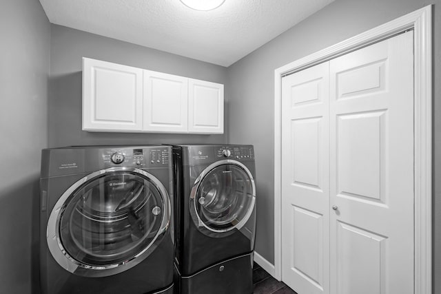 clothes washing area featuring cabinets, washer and dryer, and a textured ceiling