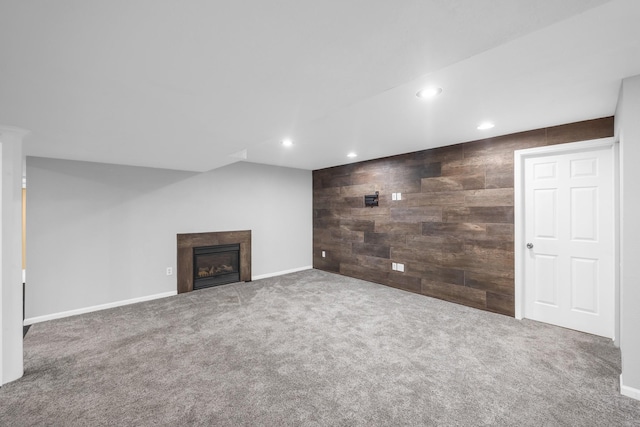 unfurnished living room with carpet flooring and wooden walls