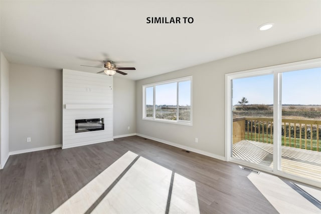 unfurnished living room with a large fireplace, baseboards, visible vents, and wood finished floors