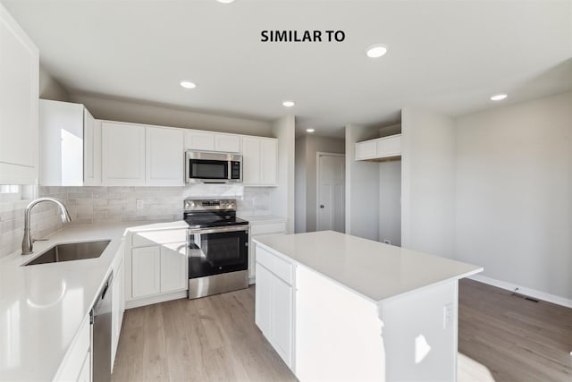 kitchen featuring sink, white cabinetry, a center island, light hardwood / wood-style flooring, and stainless steel appliances