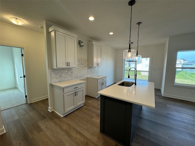 kitchen featuring a center island with sink, white cabinets, dark hardwood / wood-style floors, and sink