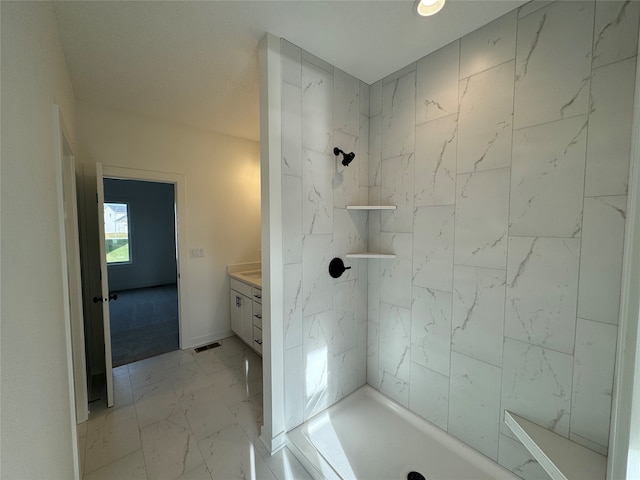 bathroom featuring a tile shower and vanity