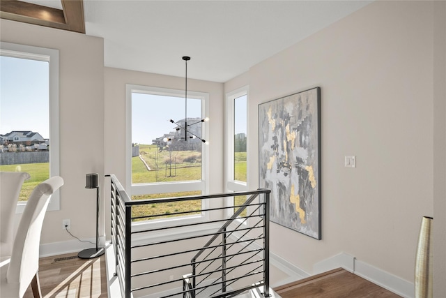 stairway with an inviting chandelier, baseboards, and wood finished floors