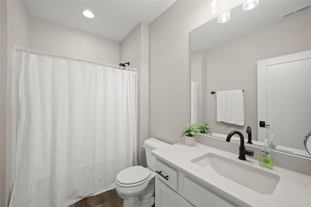 full bath with visible vents, toilet, vanity, and wood finished floors