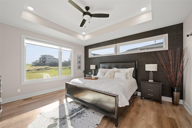 bedroom featuring visible vents, a raised ceiling, and wood finished floors