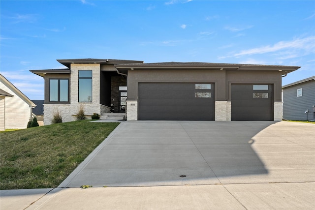 prairie-style house featuring an attached garage, stone siding, driveway, stucco siding, and a front yard