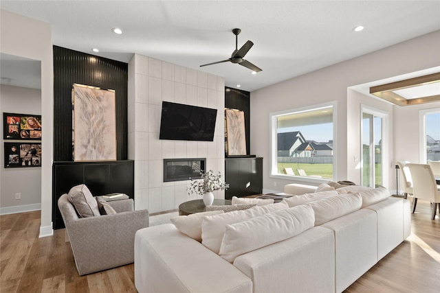 living area with a tiled fireplace, recessed lighting, baseboards, and wood finished floors