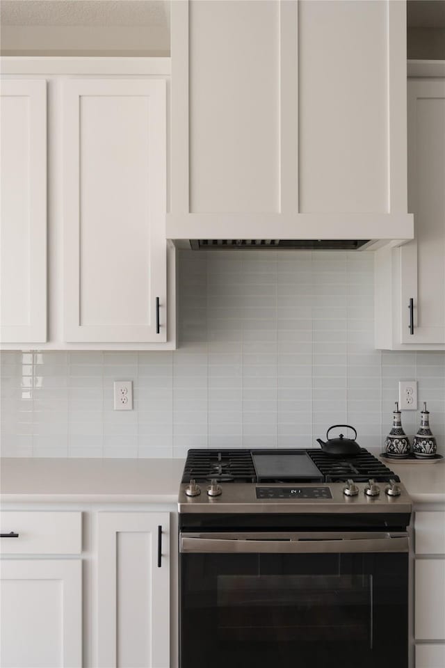 kitchen featuring range hood, white cabinets, light countertops, and stainless steel gas range