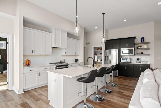 kitchen with light wood-type flooring, a sink, stainless steel appliances, a breakfast bar area, and light countertops