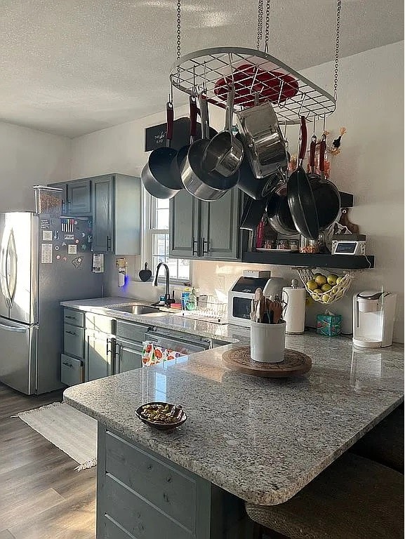 kitchen featuring a textured ceiling, stainless steel appliances, sink, hardwood / wood-style flooring, and gray cabinets