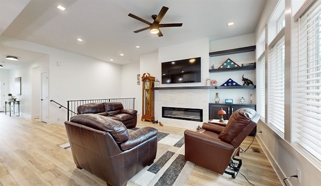 living room with ceiling fan, a healthy amount of sunlight, a fireplace, and light hardwood / wood-style flooring