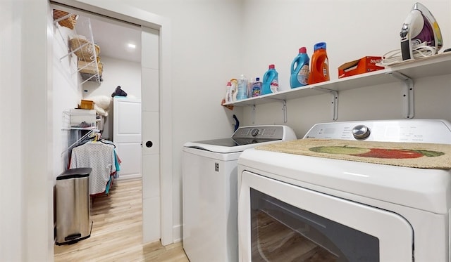 washroom with light hardwood / wood-style flooring and washing machine and clothes dryer