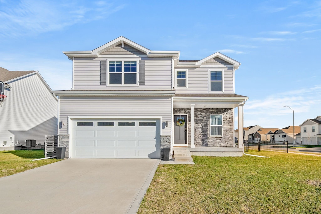 view of front of home featuring central AC, a garage, and a front yard